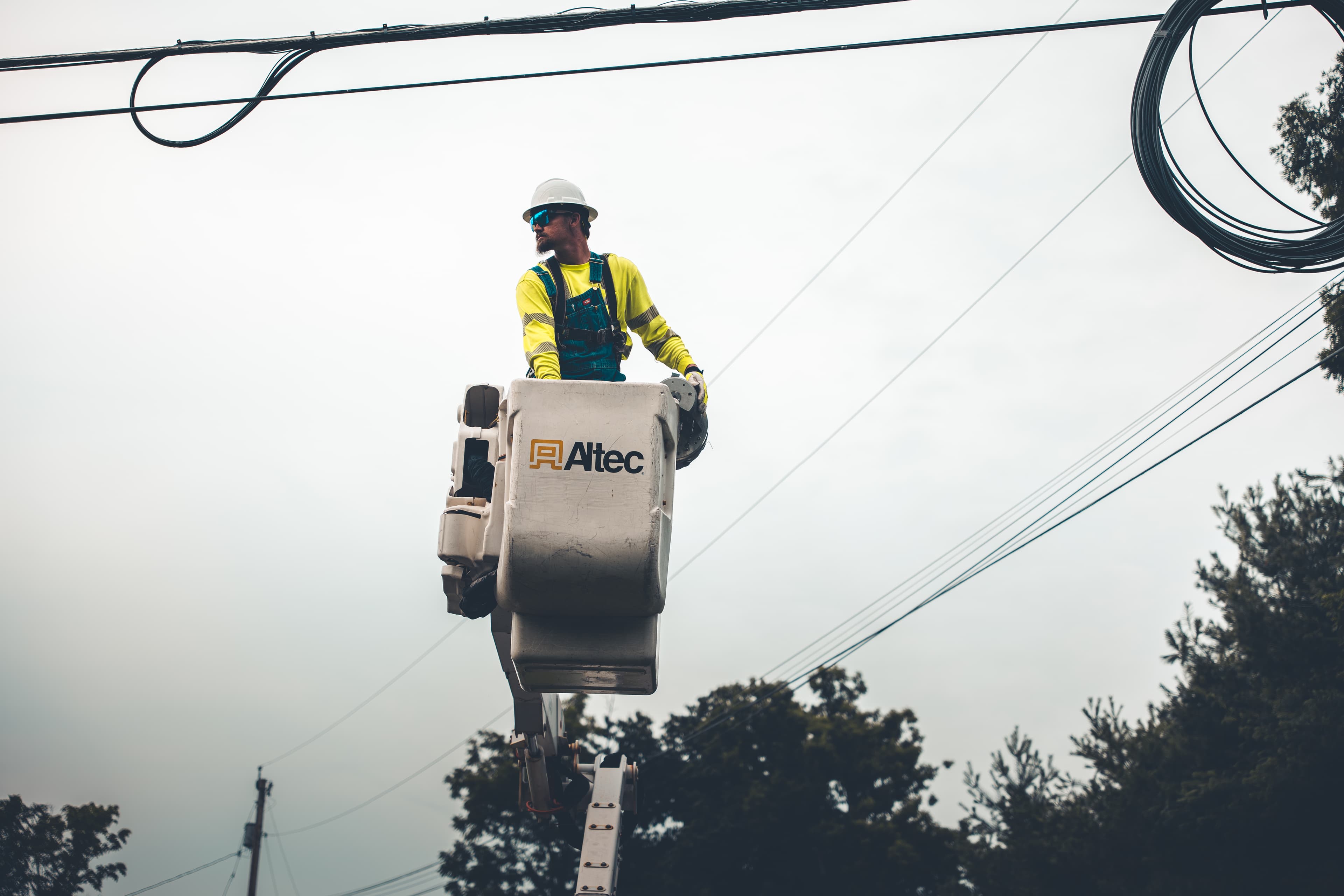 Lineman in bucket truck lashing fiber cable overhead