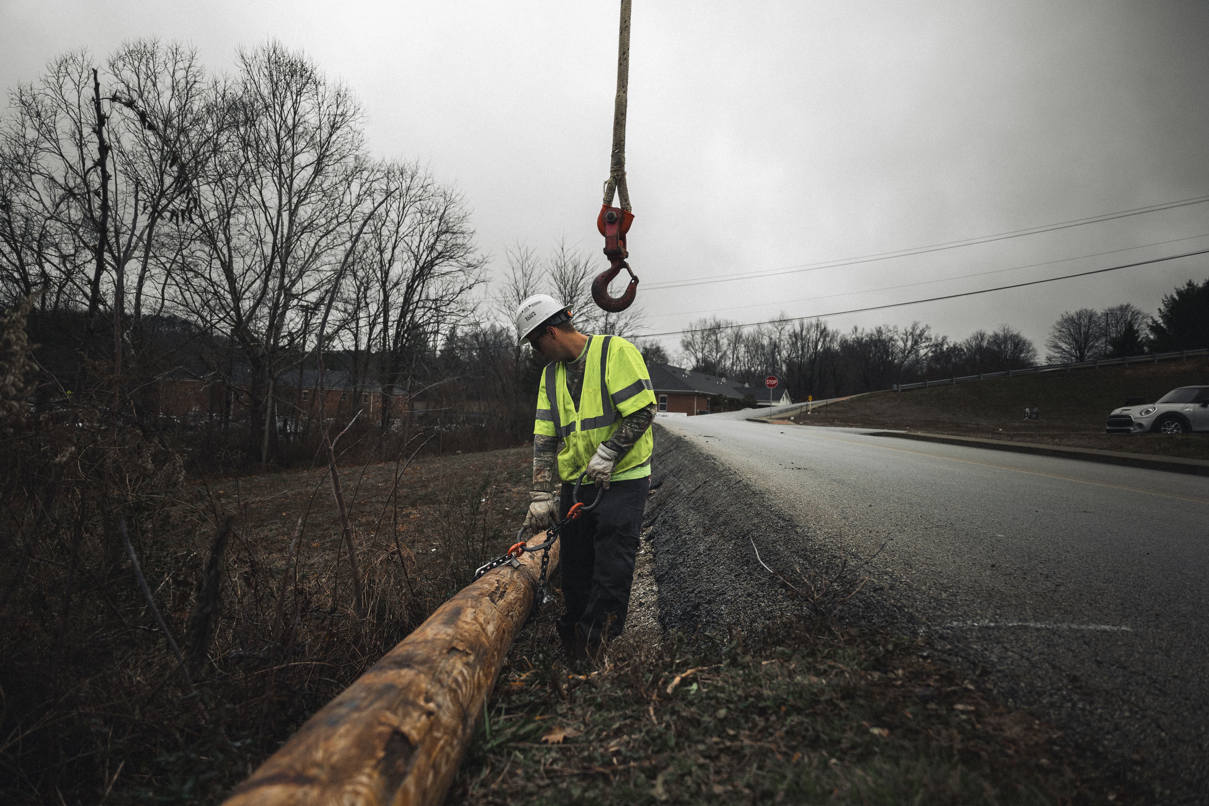 Lineman setting a transmission pole with crane